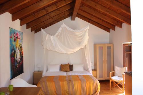 a bedroom with a bed with a mosquito net above it at Quinta Fronteira in Bensafrim