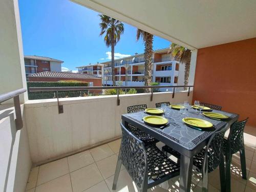 une table avec des plats jaunes sur un balcon dans l'établissement Appartement T2 front de mer avec terrasse et parking privé - FR-1-326-445, à Marseillan