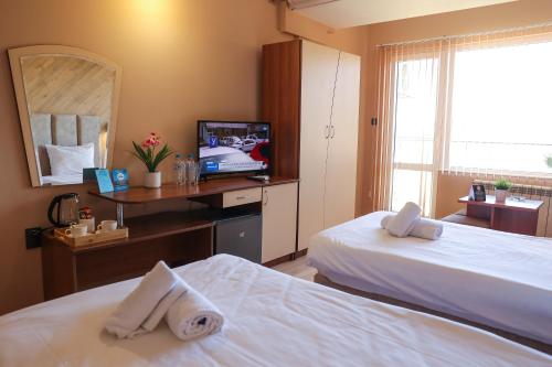 a hotel room with two beds and a television at Family Hotel Gotse Delchev in Gotse Delchev