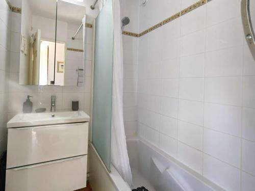 La salle de bains blanche est pourvue d'un lavabo et d'une baignoire. dans l'établissement T3 avec Terrasse, Piscine, Tennis et Parking Privé à 100m de la Plage - FR-1-607-1, au Cap d'Agde