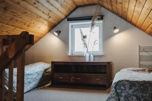 a attic bedroom with two beds and a window at Buchnas Landhotel Saarschleife in Mettlach