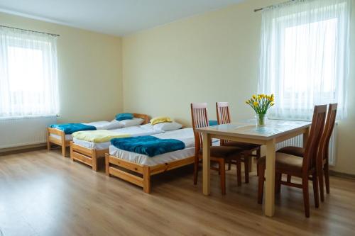 a room with two beds and a table and chairs at Noclegi Junior Wągrowiec in Wągrowiec