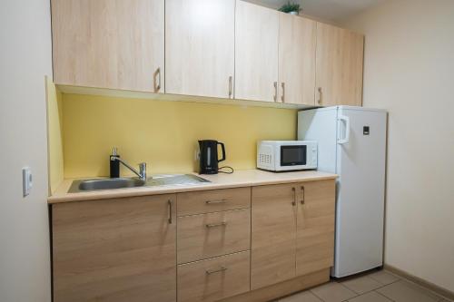 a kitchen with wooden cabinets and a white refrigerator at Noclegi Junior Wągrowiec in Wągrowiec