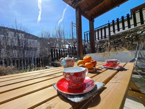 une table en bois avec deux tasses et un bol d'oranges dans l'établissement Studio confortable avec terrasse à Pra Loup, proche pistes - FR-1-165A-70, à Uvernet
