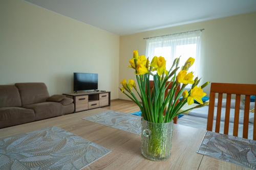 a vase of yellow flowers on a table in a living room at Noclegi Junior Wągrowiec in Wągrowiec