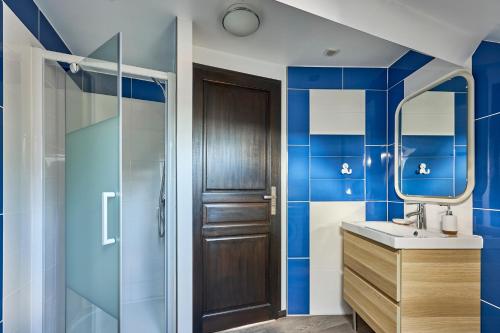 a bathroom with blue tiled walls and a wooden door at Ethoucky - Maison à 300m de la plage in Bernières-sur-Mer