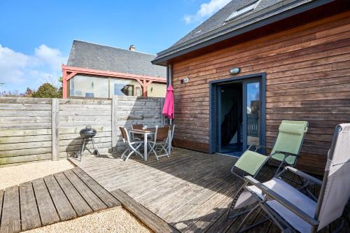 a wooden deck with chairs and a table on it at Ethoucky - Maison à 300m de la plage in Bernières-sur-Mer