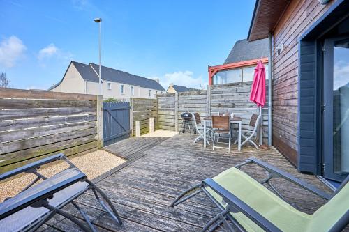 a deck with chairs and a table and a fence at Ethoucky - Maison à 300m de la plage in Bernières-sur-Mer