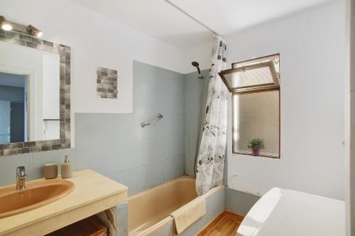 a bathroom with a tub and a sink and a mirror at Sunset Apartment in Puerto Rico de Gran Canaria