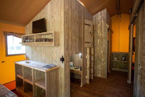 Habitación con pared de madera, puerta y baño. en Camping les Vallons de l'Océan, en La Plaine-sur-Mer