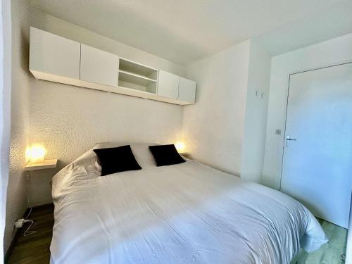 - une chambre avec un lit blanc et 2 oreillers noirs dans l'établissement Appartement Sainte-Maxime, 2 pièces, 4 personnes - FR-1-226-534, à Sainte-Maxime
