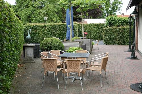 eine Terrasse mit einem Tisch, Stühlen und einem Sonnenschirm in der Unterkunft Hotel Bi-j Ons in Lichtenvoorde