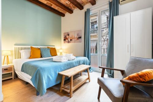 a bedroom with a bed and a chair and a table at Lodging Apartments Beach Studio P1 in Barcelona