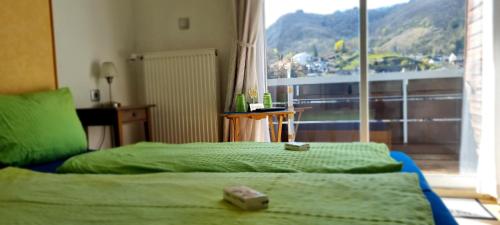 Schlafzimmer mit einem Bett mit grüner Bettwäsche und einem Fenster in der Unterkunft Pension Regina/Gräfenhaus in Cochem