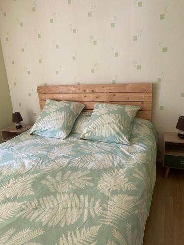 a bedroom with a bed with a wooden headboard and two pillows at Joli appartement de 60m2 avec Balcon à la campagne in Courson-les-Carrières
