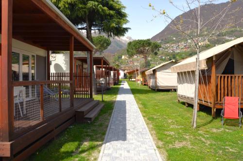 a row of lodges with a mountain in the background at GLAMPING Italia '90 Experience in Domaso