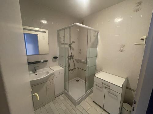 une salle de bain blanche avec une douche et un lavabo dans l'établissement LSO6096 L'Argonaute 50m de la Grande Plage, à Les Sables-dʼOlonne