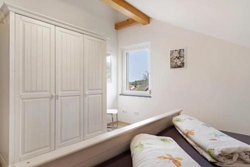 a bedroom with a large white closet and a window at Ferienwohnung In Der Weinig in Sasbach am Kaiserstuhl