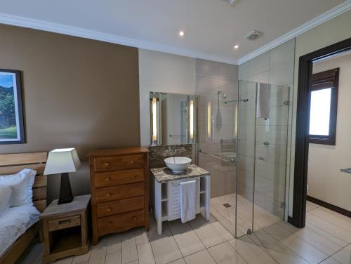 ein Bad mit einer Dusche, einem Waschbecken und einem Bett in der Unterkunft Maison Bigorno by Simply-Seychelles in Eden Island