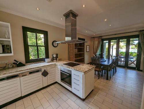a kitchen with white cabinets and a dining room with a table at Maison Bigorno by Simply-Seychelles in Eden Island