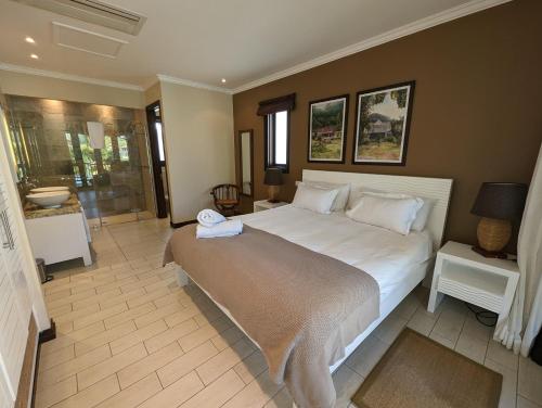 a bedroom with a large white bed and a bathroom at Maison Bigorno by Simply-Seychelles in Eden Island