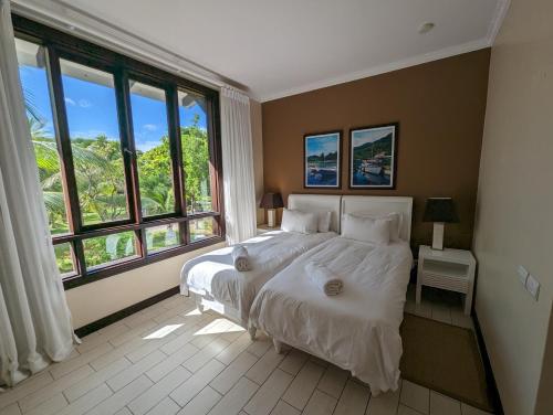 a bedroom with a large bed and large windows at Maison Bigorno by Simply-Seychelles in Eden Island