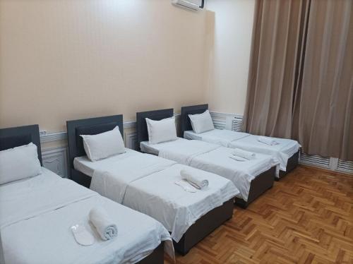 three beds in a room with white sheets at GOLDEN TRIP Hotel in Yunusobod