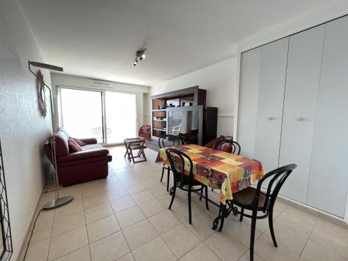 un salon avec une table, des chaises et un canapé dans l'établissement Appartement face mer - PARKING, à Les Sables-dʼOlonne