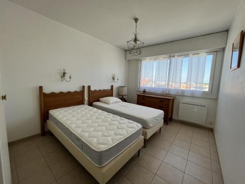 une chambre avec deux lits et une fenêtre dans l'établissement Appartement face mer - PARKING, à Les Sables-dʼOlonne