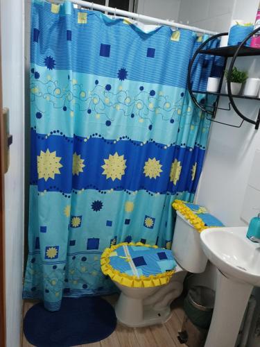 a bathroom with a blue shower curtain and a toilet at CABAÑAS BRUJAS in Salamanca