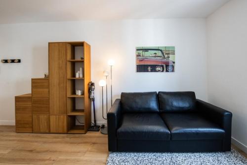 - un salon avec un canapé en cuir noir et une étagère dans l'établissement Lac Ness - Bel appartment central Part-Dieu, à Lyon