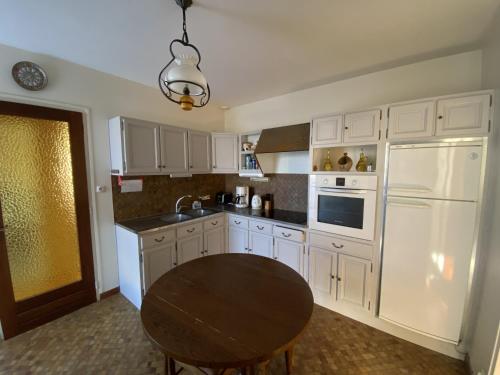 une cuisine avec des armoires blanches et une table en bois dans l'établissement Maison face mer La Chaume, à Les Sables-dʼOlonne