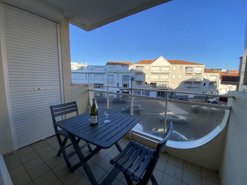 - une table avec 2 chaises et une bouteille de vin sur le balcon dans l'établissement Appartement proche plage - BALCON, à Les Sables-dʼOlonne