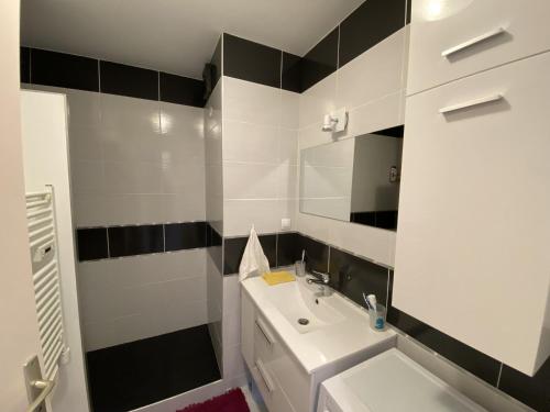 une salle de bain blanche avec un lavabo et un miroir dans l'établissement Appartement proche plage - BALCON, à Les Sables-dʼOlonne