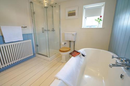 a bathroom with a shower and a toilet and a tub at 1 South Cottages in Thorpeness