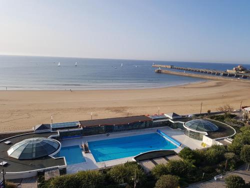 - une piscine à côté d'une plage avec une jetée dans l'établissement Appartement face mer 1 etoile - WIFI - Le Remblai, à Les Sables-dʼOlonne