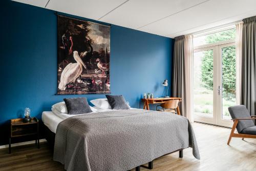 een blauwe slaapkamer met een groot schilderij aan de muur bij de Logerie in Enkhuizen
