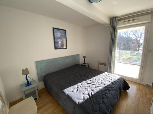 une chambre avec un lit et une grande fenêtre dans l'établissement Appartement avec piscine - La Chaume, à Les Sables-dʼOlonne