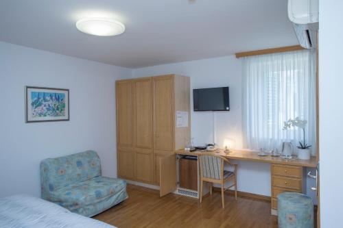 Habitación de hotel con escritorio, silla y dormitorio en Villa Ana Split, en Split