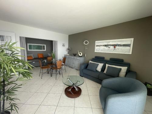 un salon avec un canapé bleu et une table dans l'établissement Appartement 2 étoiles face mer - 50m de la plage, à Les Sables-dʼOlonne