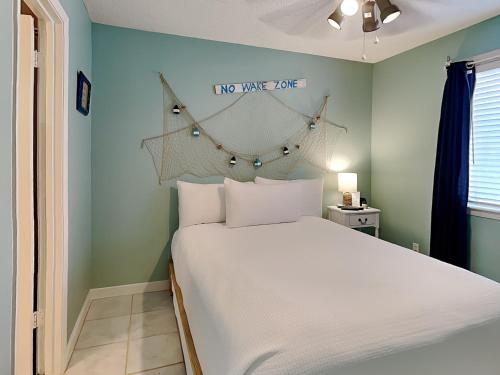 1 dormitorio con 1 cama blanca y un cartel en la pared en Island Home 102, en Destin