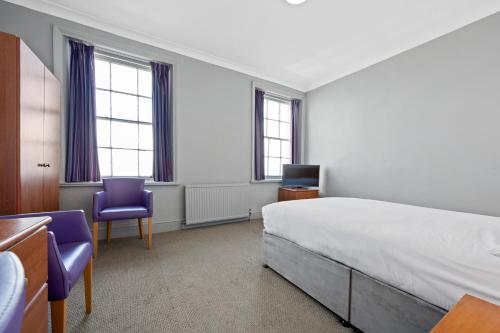 a bedroom with a bed and two purple chairs at Royal Whitby in Whitby