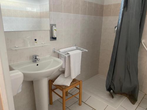 a bathroom with a sink and a shower with towels at Logis Hôtel Restaurant L'Escale in Bellême