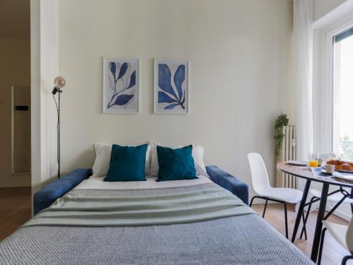 a bedroom with a bed with blue pillows and a table at The Best Rent - Morosini Apartment in Milan