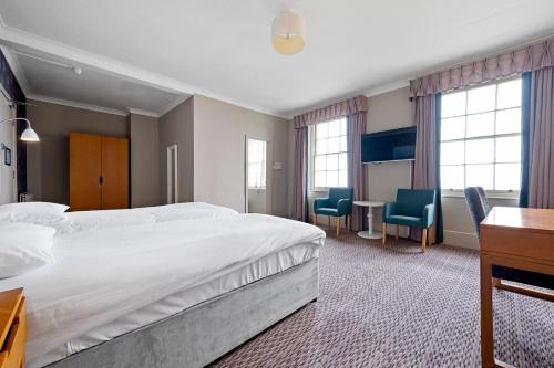 a hotel room with a bed and a desk and chairs at Royal Whitby in Whitby