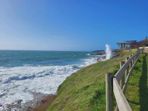 a wooden fence next to the ocean with waves at Maison de pêcheur idéalement située in Le Conquet