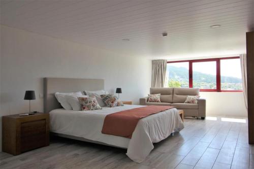 Habitación blanca con cama y sofá en 7 bedrooms villa with private pool jacuzzi and furnished garden at Terras de Bouro, en Terras de Bouro