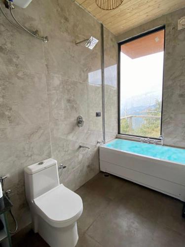 a bathroom with a toilet and a tub and a window at The Kiana's in Mussoorie