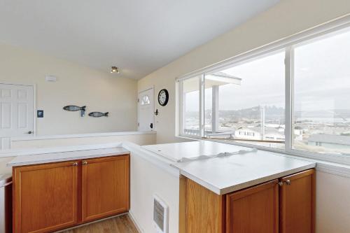uma cozinha com uma grande janela e uma bancada branca em Bayshore Modern Beach House em Waldport