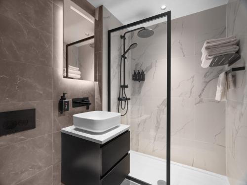 a white bathroom with a sink and a shower at Radisson RED London Gatwick Airport in Crawley